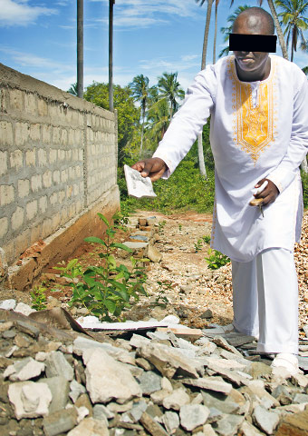 A pastor in Tanzania shows some of the rubble after his church was destroyed.
