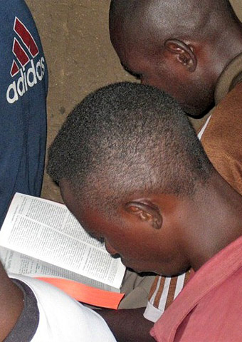 Young men from Uganda read the Bible together.