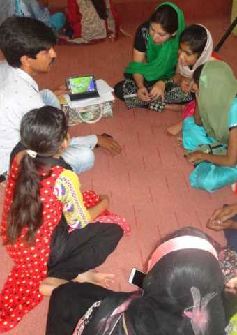 A Christian worker in Pakistan who received a Village Outreach Kit shares the gospel with a group of children.